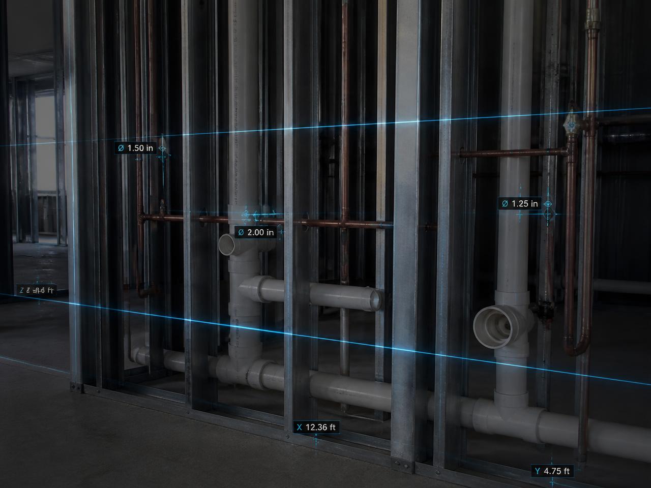Plumbing rough-in inside stud walls with blue laser lines measuring pipe diameter and position